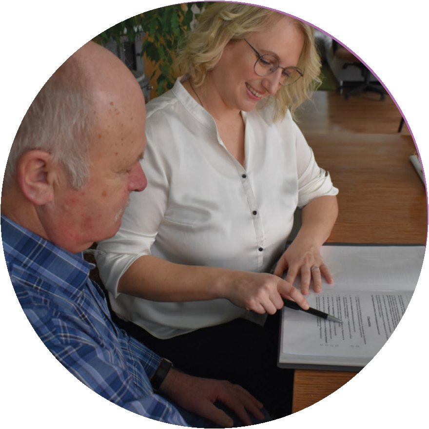 Helene Rauschecker berät einen Senior am Tisch und erklärt Unterlagen